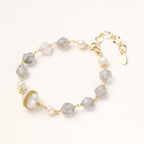Gold-plated bracelet with white freshwater pearls and translucent grey crystals, featuring mesh-wrapped baroque pearl centerpiece