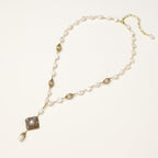 Elegant 14K gold plated necklace with freshwater pearls and ornate crystal diamond pendant on cream background.