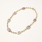 Long gold-plated necklace with iridescent baroque pearls and round freshwater pearls on cream background