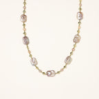 Long gold-plated necklace with iridescent baroque pearls and round freshwater pearls on cream background