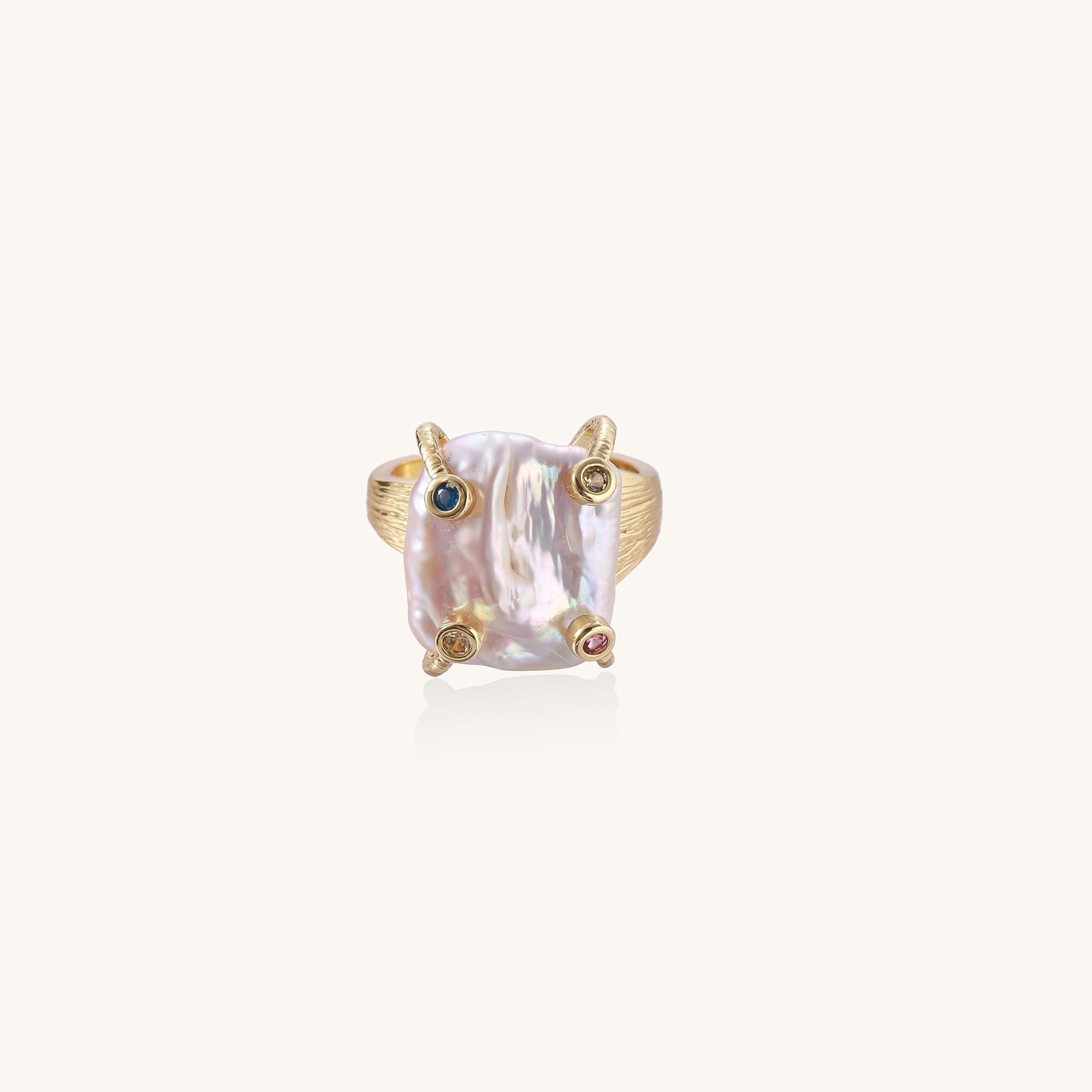 Gold-plated ring featuring large baroque freshwater pearl with small colorful gemstone accents on textured band