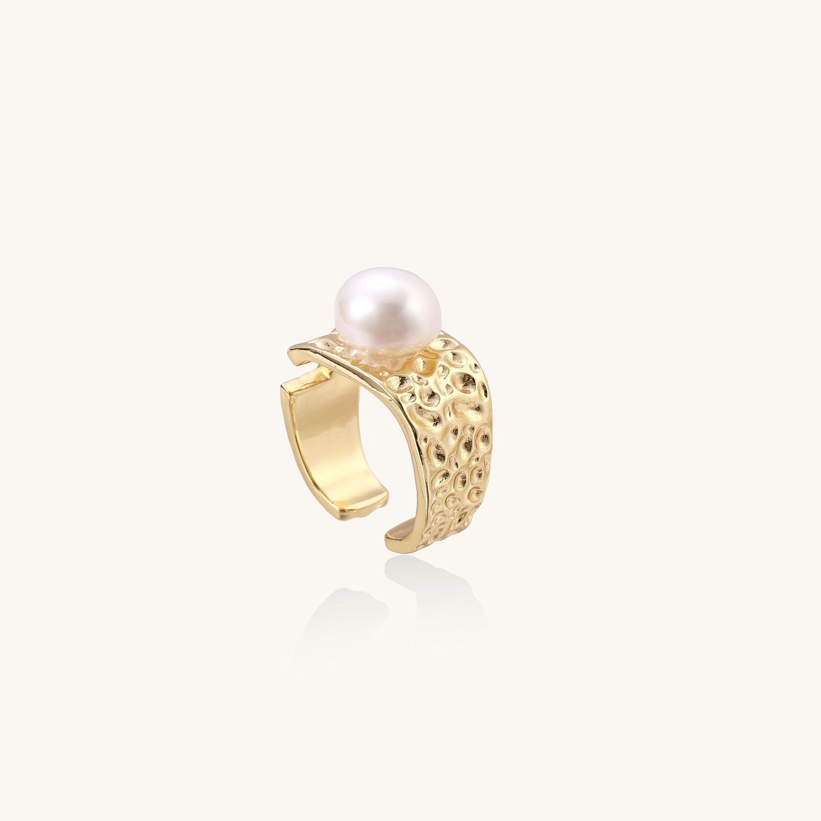 Wide textured gold-plated brass ring with round freshwater pearl centerpiece on neutral background