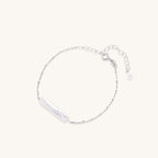 Delicate sterling silver chain bracelet with an organic white baroque pearl centerpiece on neutral background