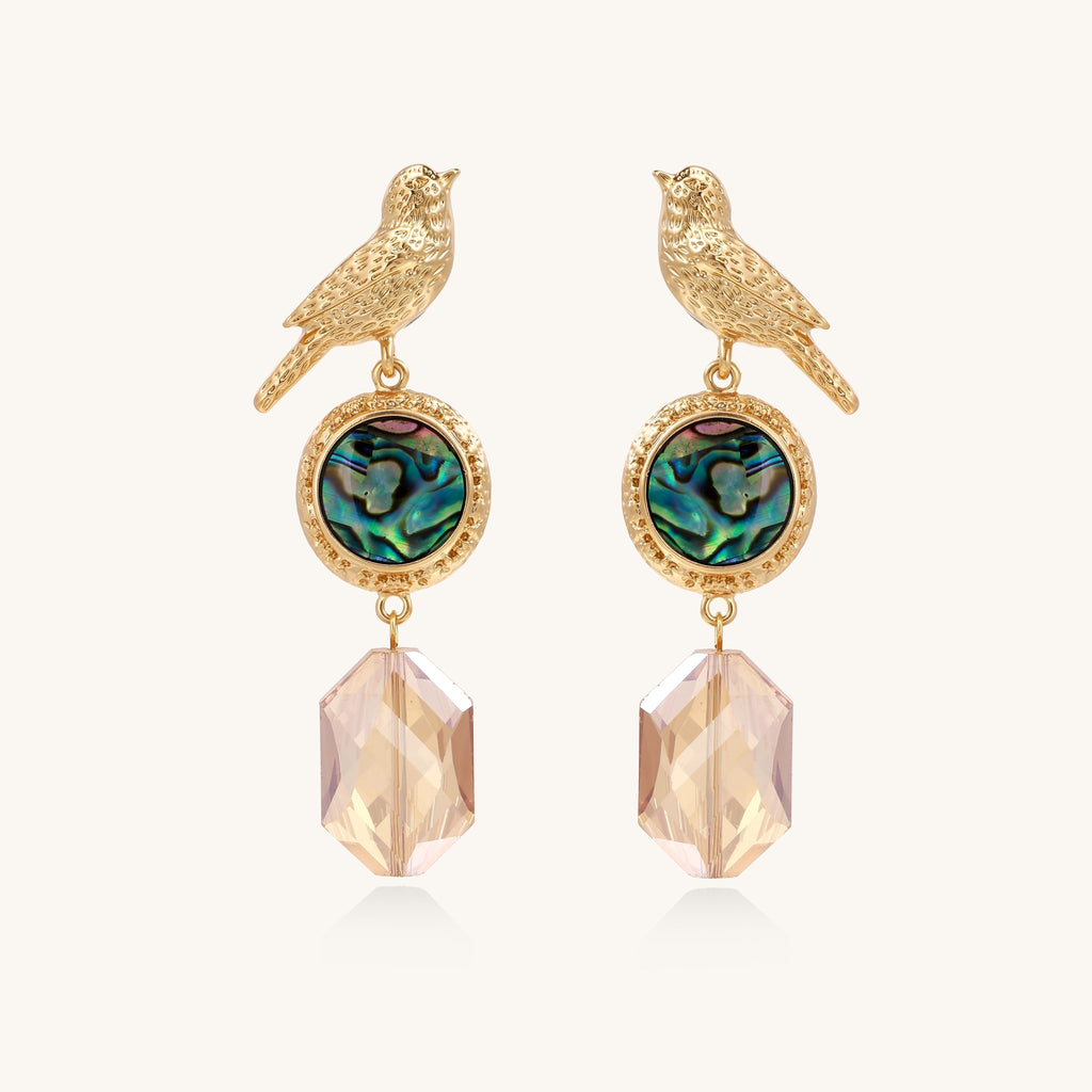 Gold-plated bird dangle earrings with iridescent abalone shell discs and champagne crystal drops on white background.