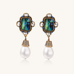 Gold-plated brass drop earrings featuring iridescent abalone shell centers, crystal accents, and white pearl drops.