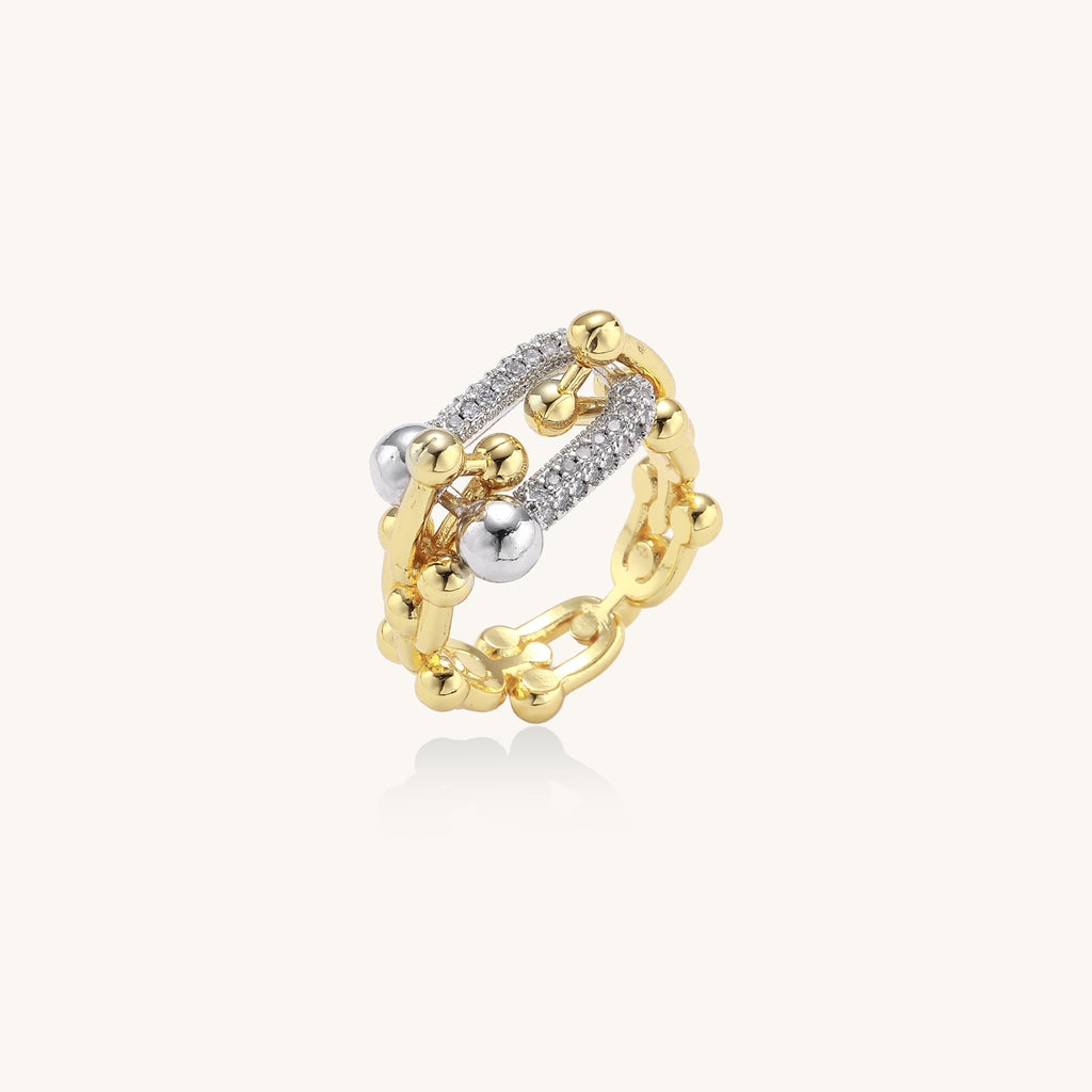 Bold gold-plated chain-link ring with cubic zirconia bars and sphere details on white background.