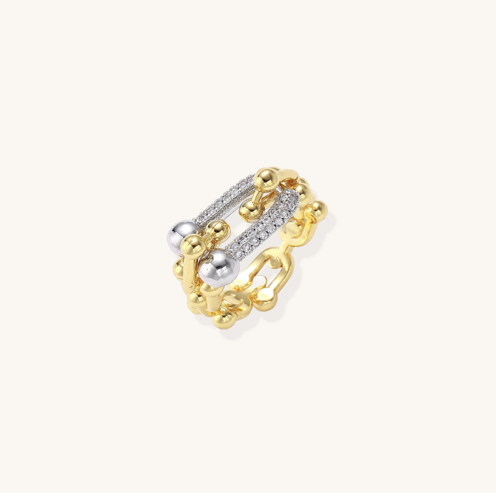 Bold gold-plated chain-link ring with cubic zirconia bars and sphere details on white background.