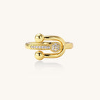 Modern gold-plated adjustable ring with safety pin design and sparkling cubic zirconia accents on white background