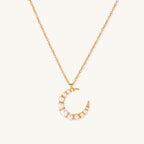 Delicate 18K gold plated necklace featuring crescent moon pendant with white shell pearl beads on neutral background.