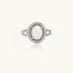 Gold-plated ring with oval cat's eye stone center, blue accent stones, and crystal halo on white background.